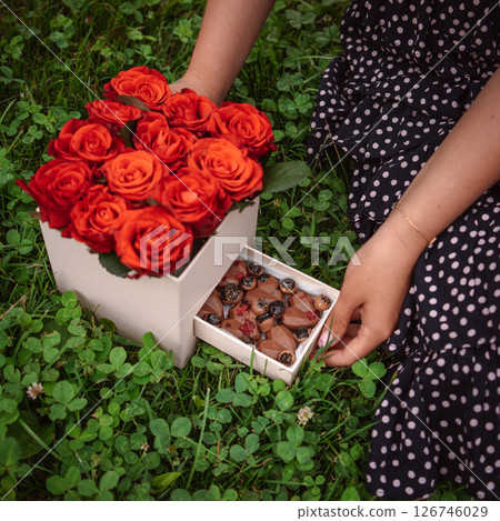 Gifts of Affection: Box of Flowers and Chocolate, Embraced by Hands and Attire Gifts of Affection: Box of Flowers and Chocolate, Embraced by Hands and Attire 126746029
