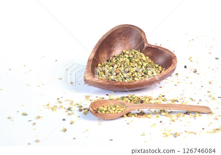 Crushed pistachio nuts in wooden bowl and heart-shaped spoon for cooking. Environmentally friendly product and health. Crushed pistachio nuts in wooden bowl and heart-shaped spoon for cooking. Environmentally friendly product and health. 126746084