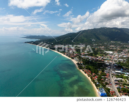 Aerial view of a coastal village surrounded by green hills and clear turquoise waters under a sunny sky. Koh Samui, Thailand. Aerial view of a coastal village surrounded by green hills and clear turquoise waters under a sunny sky. Koh Samui, Thailand. 126746423