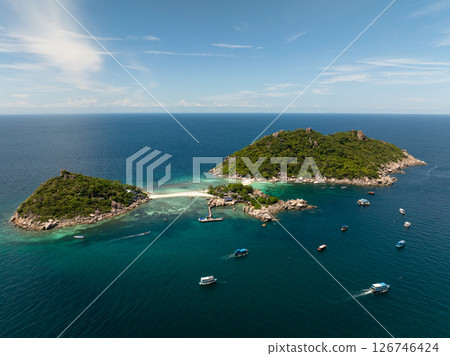 Lush tropical hills meet vibrant blue waters under sunny skies, offering a serene paradise. Thailand, Koh Tao. 126746424