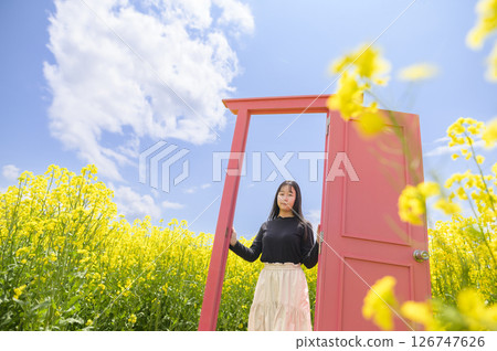 A woman sightseeing in a rapeseed field in full bloom (pink door) 126747626