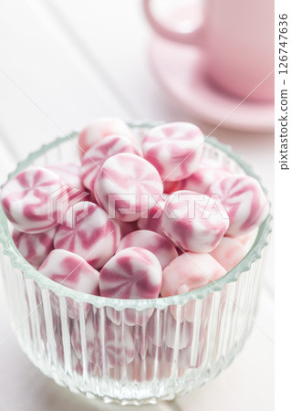 Colorful striped candies in bowl on white table. 126747636