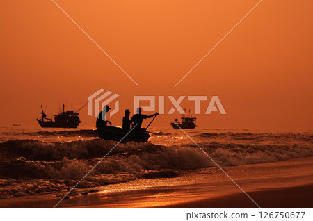 Silhouettes of Vietnamese fishermen on baskets boats and fishing ships at sea in the morning at sunrise in Vietnam 126750677