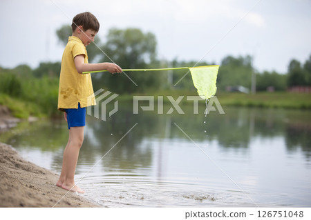 A little boy with a butterfly net is fishing in the lake. 126751048