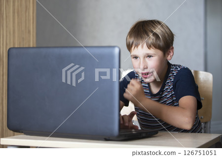 Schoolboy during online lesson at home, social distance during quarantine, self-isolation, online education concept. Elementary age boy at laptop at home. Schoolboy during online lesson at home, social distance during quarantine, self-isolation, online education concept. Elementary age boy at laptop at home. 126751051
