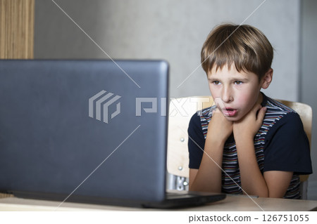 Schoolboy during online lesson at home, social distance during quarantine, self-isolation, online education concept. Elementary age boy at laptop at home. 126751055