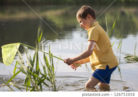 A little boy with a butterfly net catches fry in the lake. A little boy with a butterfly net catches fry in the lake. 126751058