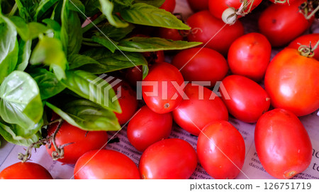 Fresh, juicy Tomatoes and aromatic Basil elegantly displayed on Newspaper for all to enjoy Fresh, juicy Tomatoes and aromatic Basil elegantly displayed on Newspaper for all to enjoy 126751719