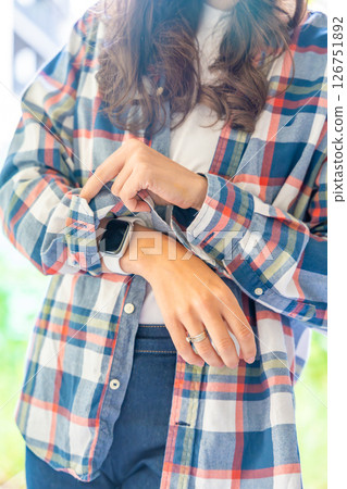 Woman adjusting sleeves on a plaid shirt, captured from neck to mid-thigh. Concept of casual fashion, self-care and daily clothing routine. Woman adjusting sleeves on a plaid shirt, captured from neck to mid-thigh. Concept of casual fashion, self-care and daily clothing routine. 126751892