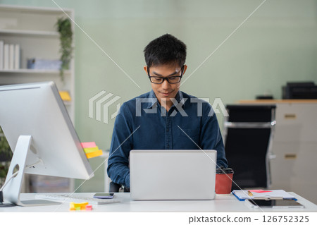Businessman using laptop computer in office. Happy man, entrepreneur, small business owner working online. 126752325