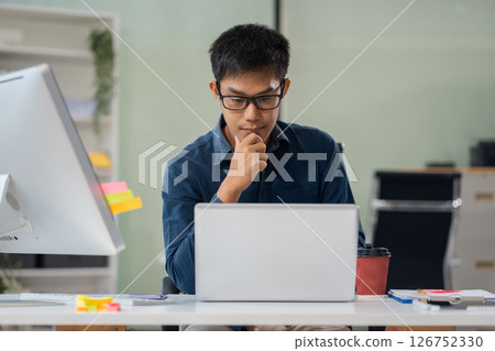 Businessman using laptop computer in office. Happy man, entrepreneur, small business owner working online. Businessman using laptop computer in office. Happy man, entrepreneur, small business owner working online. 126752330