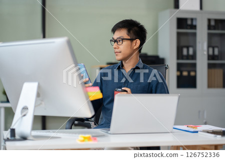 Male are using a mobile phone wifi connection tablet on the desk with a cup of coffee in the morning. Male are using a mobile phone wifi connection tablet on the desk with a cup of coffee in the morning. 126752336