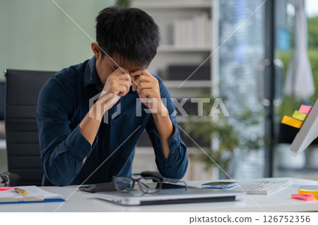 stressed asian businessman working in the office. Businessman thinking too much work concept in the office. stressed asian businessman working in the office. Businessman thinking too much work concept in the office. 126752356