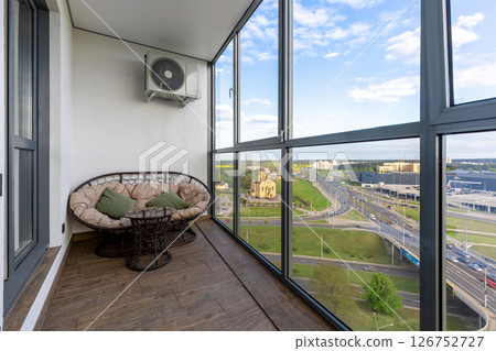 Glazed Balcony with Rattan Lounge and Cityscape 126752727