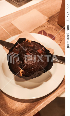 Delicious chocolate muffin with chocolate chips on a plate in prague Delicious chocolate muffin with chocolate chips on a plate in prague 126752882