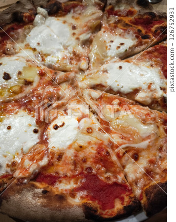 Wood fired pizza featuring melting cheese, rich tomato sauce, golden brown crust with crispy bubbling edges and savory toppings 126752931