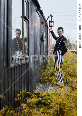 A captivating portrait with a vintage lantern and striped pants, evoking mystery and whimsy 126753106