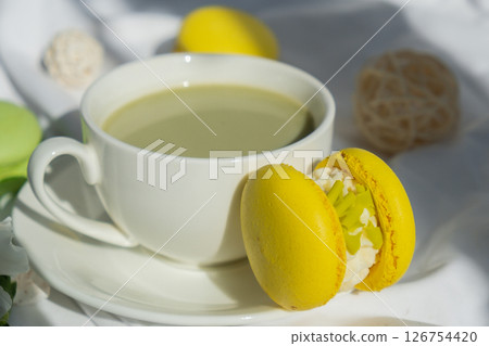 Sweet yellow macaron dessert Cup of green plant based matcha tea latte in cozy morning bed atmosphere. Creative holiday romantic date idea. Herbal prebiotic fiber superfood beverage antioxidant-rich 126754420