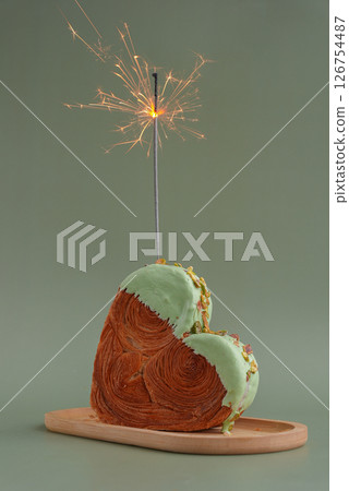 Shiny festive candle sparkler birthday celebration holiday Delightful and vibrant heartshaped pastry croissant treat, beautifully topped with colorful frosting nut galore. Mock up template copy space 126754487