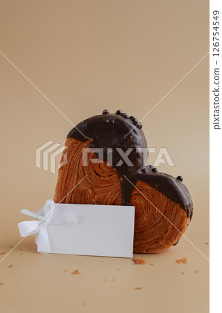 Empty paper note template mock up Heart shaped dark chocolate croissant on beige background with copy space. Puff pastry new trendy sweet dessert bakery. Creamy dough 126754549
