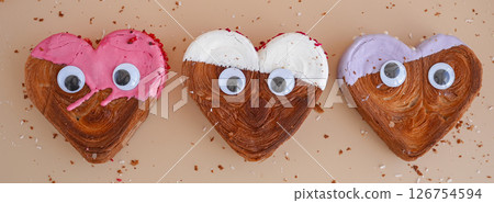 Funny food game face with crazy eyes April fool day joke Delightful and vibrant heartshaped pastry croissant treat, beautifully topped with colorful frosting galore. Food experimentation dessert 126754594