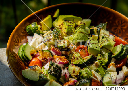 Avocado mix of vegetables salad in daytime outdoors. Fresh salad with tomatoes, avocado, lettuce onion cucumber. Healthy and detox food concept. Ketogenic diet Avocado mix of vegetables salad in daytime outdoors. Fresh salad with tomatoes, avocado, lettuce onion cucumber. Healthy and detox food concept. Ketogenic diet 126754693