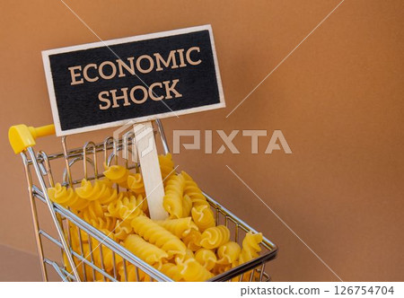 ECONOMIC SHOCK text on Blackboard label against Shopping trolley cart Filled With Pasta on Beige background. Food and groceries shopping price increase, Rising food cost food crisis inflation ECONOMIC SHOCK text on Blackboard label against Shopping trolley cart Filled With Pasta on Beige background. Food and groceries shopping price increase, Rising food cost food crisis inflation 126754704