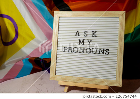 ASK MY PRONOUNS text Neo pronouns concept on Rainbow flag background gender pronouns. Non-binary people rights transgenders. Lgbtq community support assume my gender tolerance equal rights ASK MY PRONOUNS text Neo pronouns concept on Rainbow flag background gender pronouns. Non-binary people rights transgenders. Lgbtq community support assume my gender tolerance equal rights 126754744