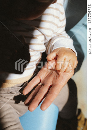 Child Grasping Adult Hand in Warm Sunlit Moment 126754758