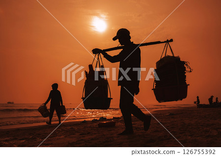 silhouette of Vietnamese male porter at the fish market at the port in a fishing village in morning at sunrise in Vietnam silhouette of Vietnamese male porter at the fish market at the port in a fishing village in morning at sunrise in Vietnam 126755392