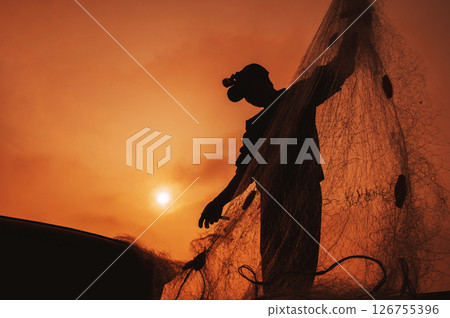 Silhouette of a Vietnamese male fisherman taking out a catch of fish from fishing net in boat on beach by the sea in a fishing village in the morning at sunrise in Vietnam Silhouette of a Vietnamese male fisherman taking out a catch of fish from fishing net in boat on beach by the sea in a fishing village in the morning at sunrise in Vietnam 126755396