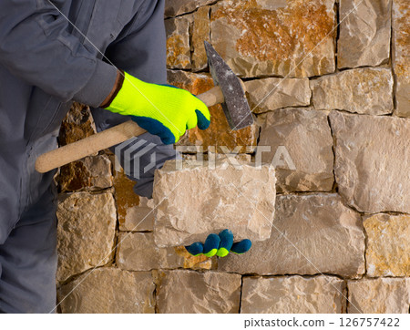 stonecutter mason with hammer and stone working masonry 126757422
