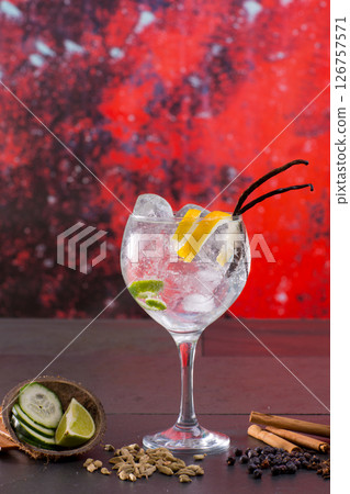 Gin tonic cocktail with spices in red grunge background Gin tonic cocktail with spices in red grunge background 126757571