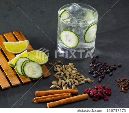 Gin tonic cocktail with cucumber cloves cardamom cinnamon and juniper Gin tonic cocktail with cucumber cloves cardamom cinnamon and juniper 126757573