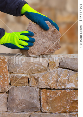 Mason hands working on masonry stone wall 126757594
