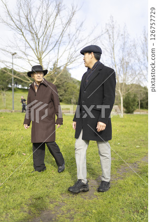Two senior men walking and talking in a park Two senior men walking and talking in a park 126757729
