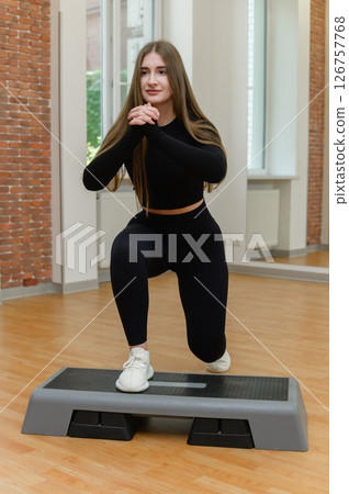 Young woman doing step-up workout on aerobic platform. 126757768