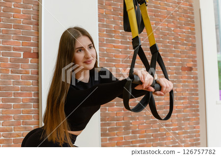 Young woman training with trx fitness straps in the gym. Young woman training with trx fitness straps in the gym. 126757782