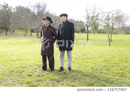 Father and son standing together in park during winter day 126757907
