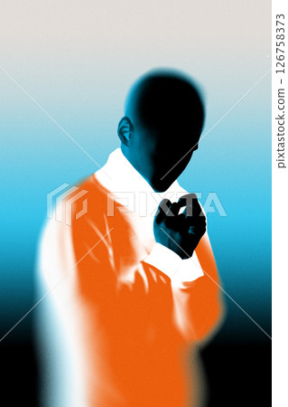 Dark silhouette of figure, with hands clasped near chest, against blue and orange gradient background. 126758373
