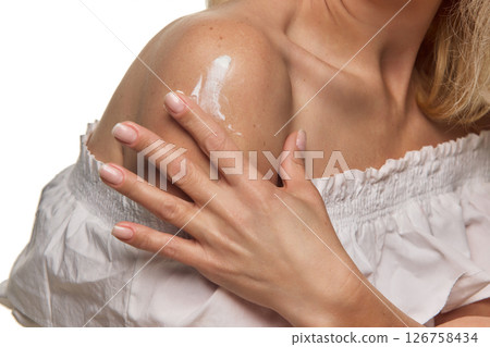 Close-up of woman's hand applying creamy lotion, cosmetic product on shoulder with gentle touch Close-up of woman's hand applying creamy lotion, cosmetic product on shoulder with gentle touch 126758434