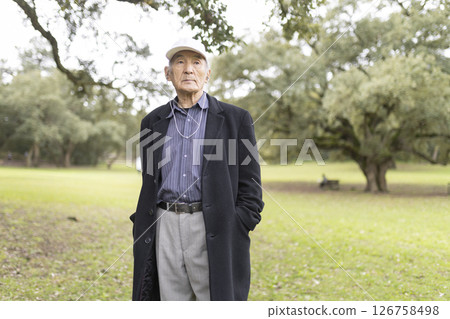Elderly asian man wearing a hat and coat in a park 126758498