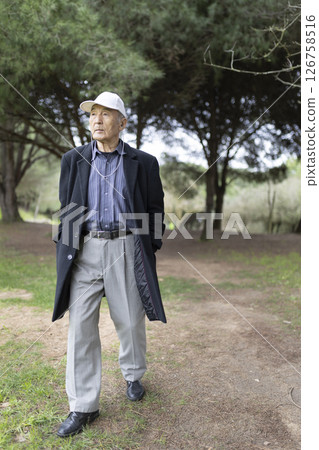 Elderly asian man walking in park wearing headphones and cap Elderly asian man walking in park wearing headphones and cap 126758516