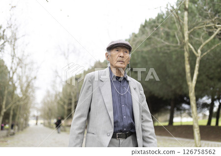 Elderly man listening music walking in park during winter 126758562