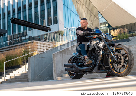 Handsome motorcyclist without helmet sitting on his moto against urban background. High quality photo Handsome motorcyclist without helmet sitting on his moto against urban background. High quality photo 126758646