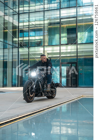 Handsome motorcyclist biker without helmet sitting on his moto against urban background. High quality photo 126758661
