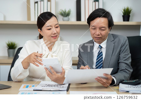 Business Collaboration and Financial Discussion. Two professionals reviewing financial reports in a modern office. 126759632