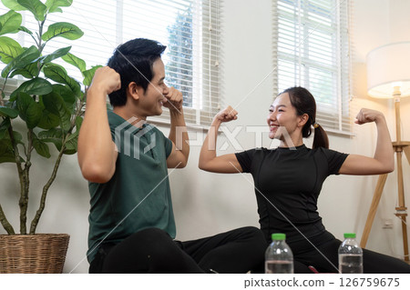 Couple showcasing strength and joy while exercising together at home. 126759675