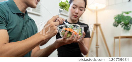 Couple Enjoying Healthy Meal. Two fitness enthusiasts sharing a nutritious salad after workout. 126759684