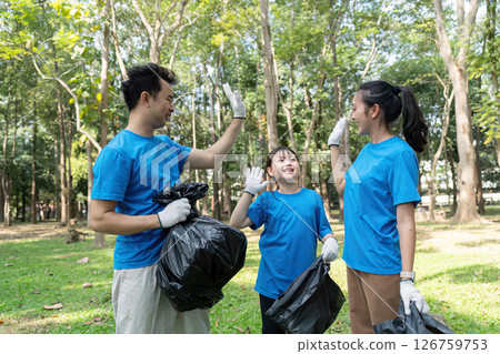 Family celebrating teamwork while volunteering for garbage collection in a park, fostering community spirit and environmental care. Family celebrating teamwork while volunteering for garbage collection in a park, fostering community spirit and environmental care. 126759753